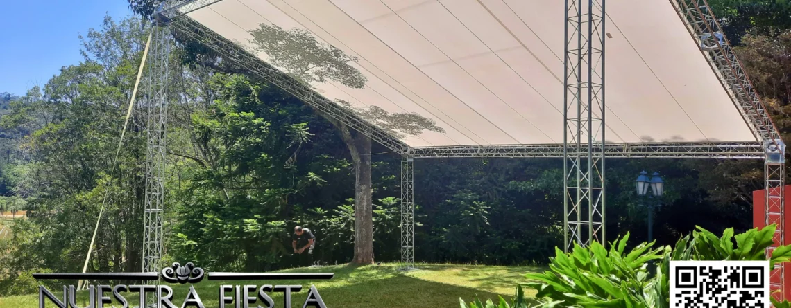 Tenda modelo 'uma água' da NUESTRA FIESTA montada em um jardim verdejante, cobrindo um palco que será instalado abaixo.