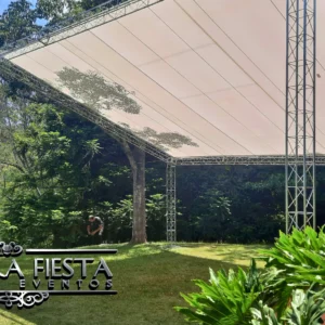 Tenda modelo 'uma água' da NUESTRA FIESTA montada em um jardim verdejante, cobrindo um palco que será instalado abaixo.