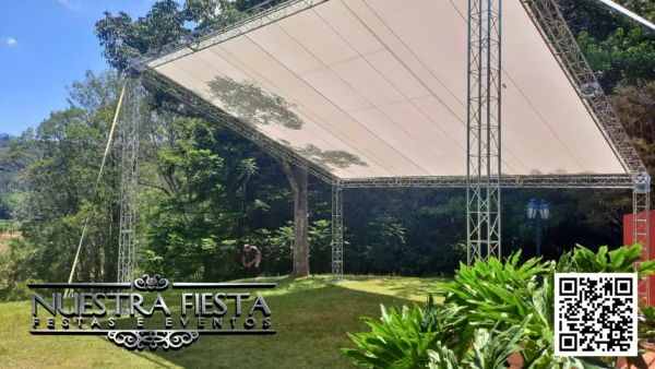 Tenda modelo 'uma água' da NUESTRA FIESTA montada em um jardim verdejante, cobrindo um palco que será instalado abaixo.