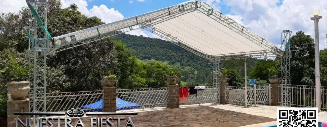 Tenda da NUESTRA FIESTA montada ao lado de uma piscina, proporcionando sombra em um ambiente relaxante ao ar livre.