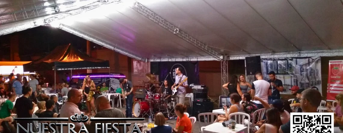 Tenda da NUESTRA FIESTA em um evento, abrigando um pequeno palco montado para apresentações.