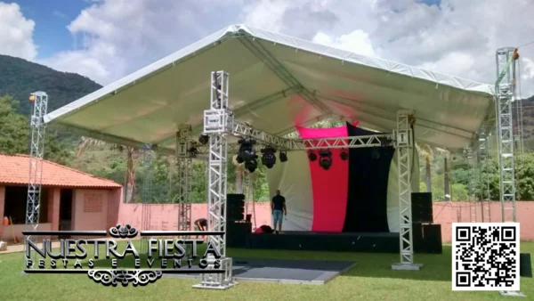 Tenda de 12x12 metros com altura lateral de 5 metros da NUESTRA FIESTA, cobrindo um palco com sistema de iluminação instalado abaixo.