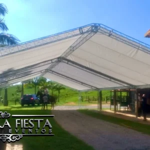 Tenda branca da NUESTRA FIESTA montada em um jardim verde, ideal para eventos ao ar livre.