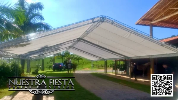 Tenda branca da NUESTRA FIESTA montada em um jardim verde, ideal para eventos ao ar livre.
