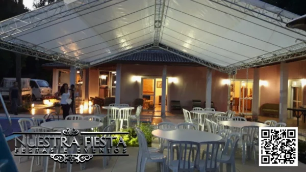 Tenda pequena da NUESTRA FIESTA iluminada à noite, proporcionando um ambiente acolhedor para um encontro familiar.