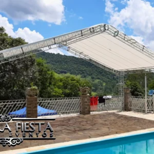 Tenda da NUESTRA FIESTA montada ao lado de uma piscina, proporcionando sombra em um ambiente relaxante ao ar livre.