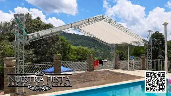 Tenda da NUESTRA FIESTA montada ao lado de uma piscina, proporcionando sombra em um ambiente relaxante ao ar livre.