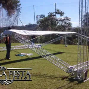 Estrutura semi montada da tenda NUESTRA FIESTA em um campo de futebol, demonstrando o processo de montagem.