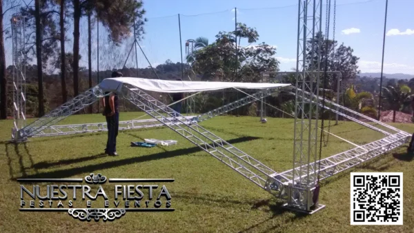Estrutura semi montada da tenda NUESTRA FIESTA em um campo de futebol, demonstrando o processo de montagem.
