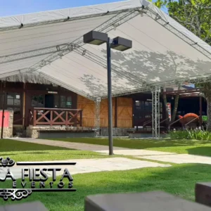 Tenda da NUESTRA FIESTA montada no jardim de um restaurante, criando um espaço elegante e acolhedor ao ar livre.